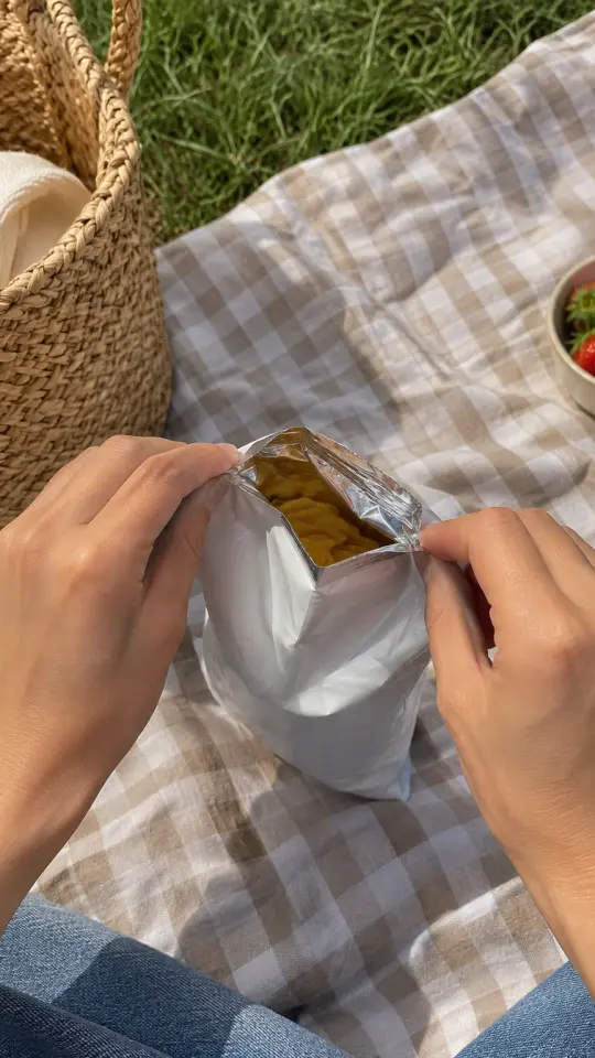 Illustration: hands opening a snack bag on a picnic blanket